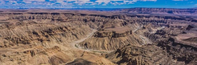Große Schluchtenlandschaft mit hohen Felsen und tiefer Schlucht unter leicht bewölktem Himmel