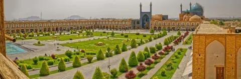 Luftaufnahme eines Platzes mit grüner Wiese und Pflanzen, umringt von einer Mauer und einer Moschee mit Kuppel