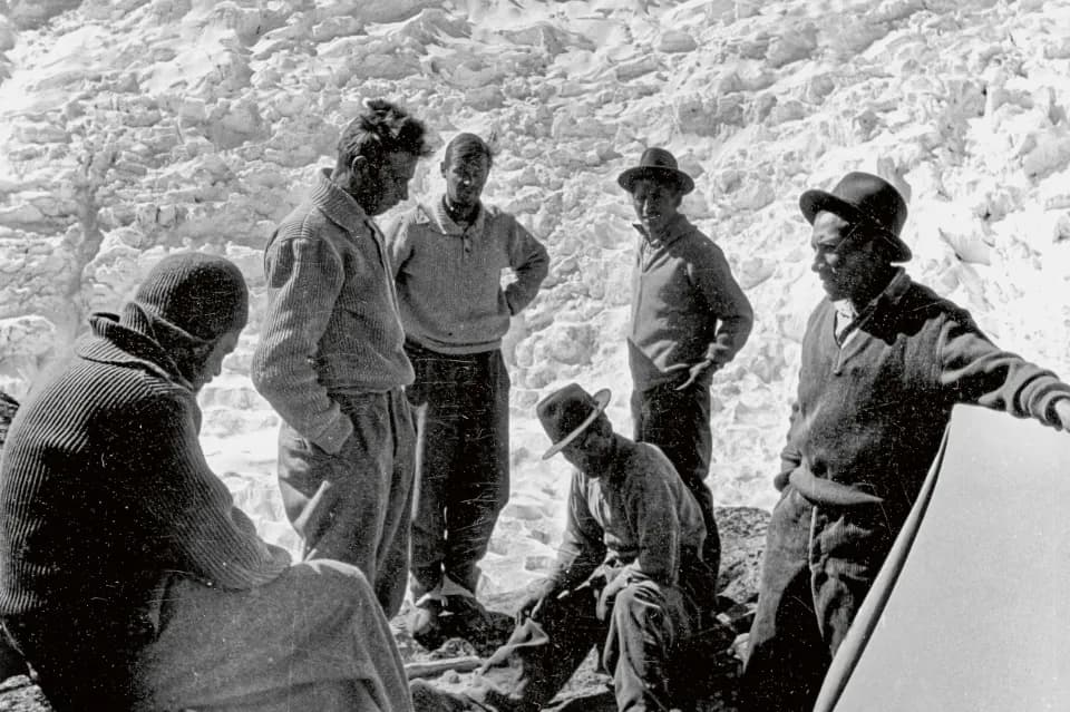 Eine Gruppe von Bergsteigern steht im Kreis und bespricht sich