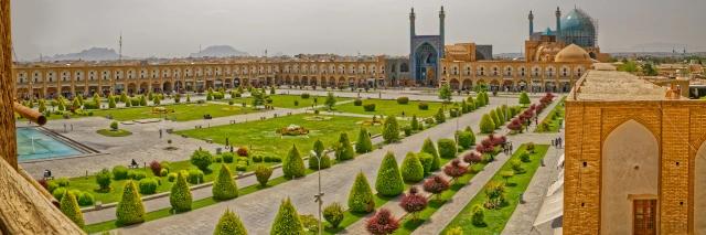 Luftaufnahme eines Platzes mit grüner Wiese und Pflanzen, umringt von einer Mauer und einer Moschee mit Kuppel