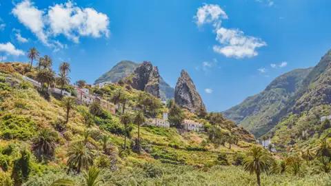 Ein Dorf inmitten einer hügeligen Landschaft mit Palmen und einzigartigen Felsformationen.