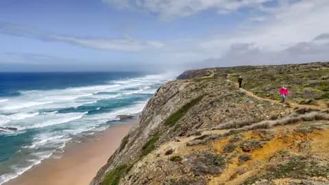 Wanderer auf einem Pfad entlang der Küste mit Blick auf den Ozean und die Wellen.